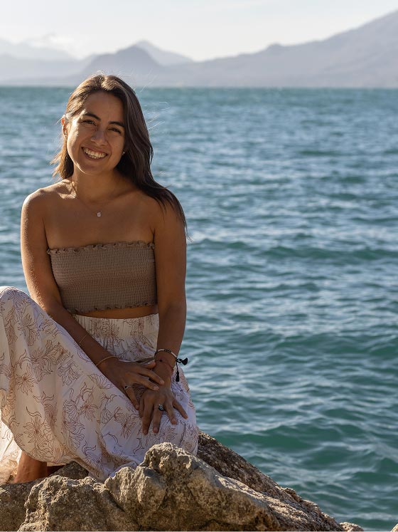 Melanie Benítez, terapeuta de bienestar integral, sentada frente al mar